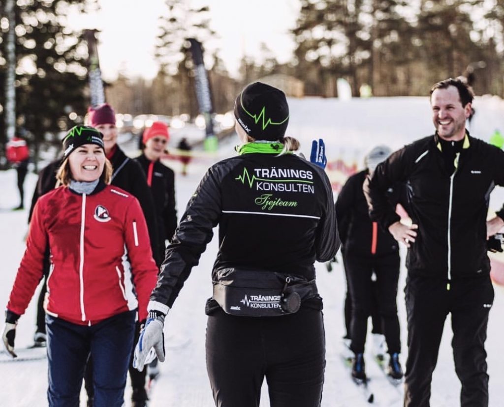 Glada skidåkare i grupp tränar stakåkning utan stavar med ledare