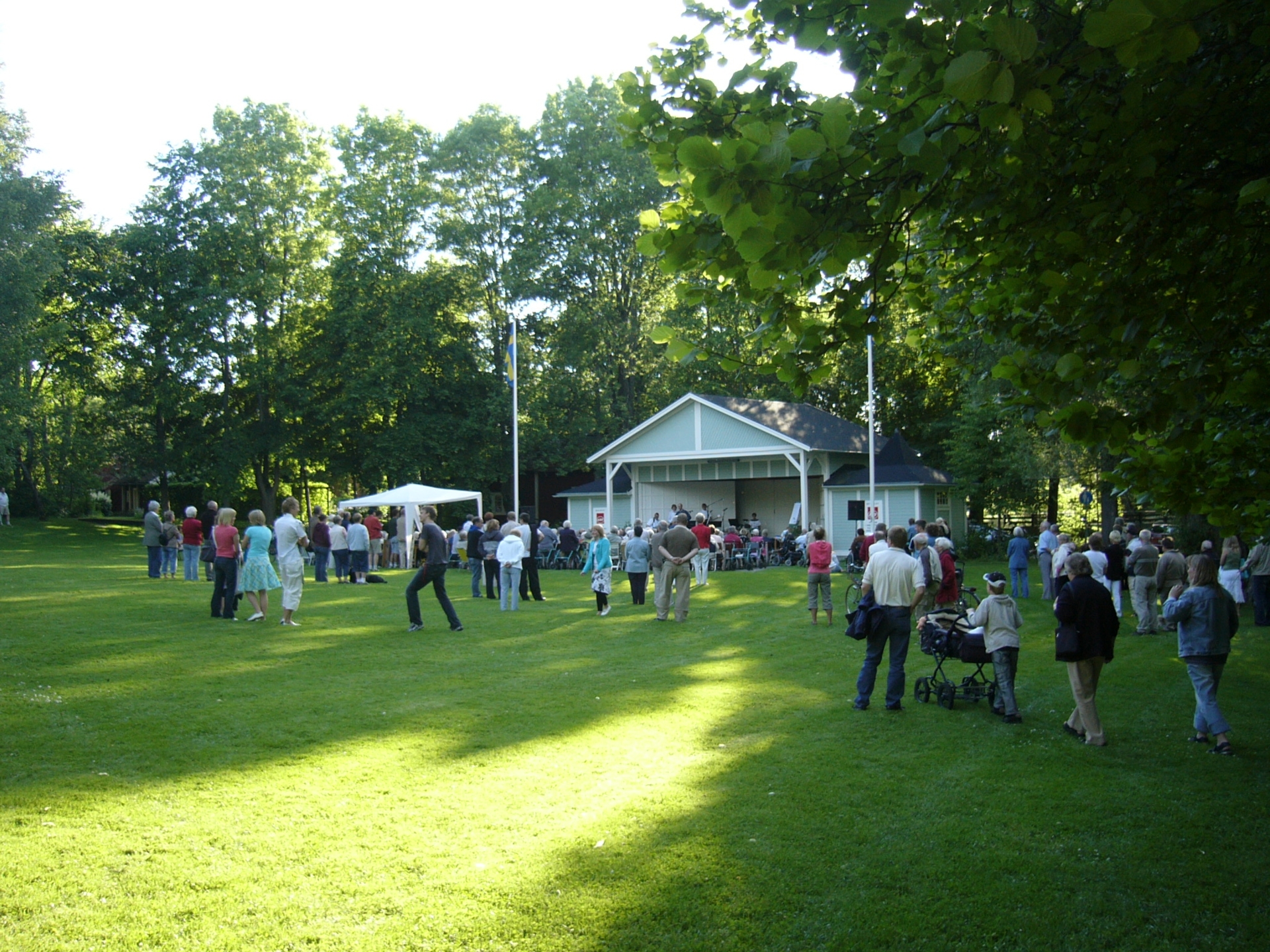 People who listen to a performance in Bruksville Park in Tidaholm a summer evening.
