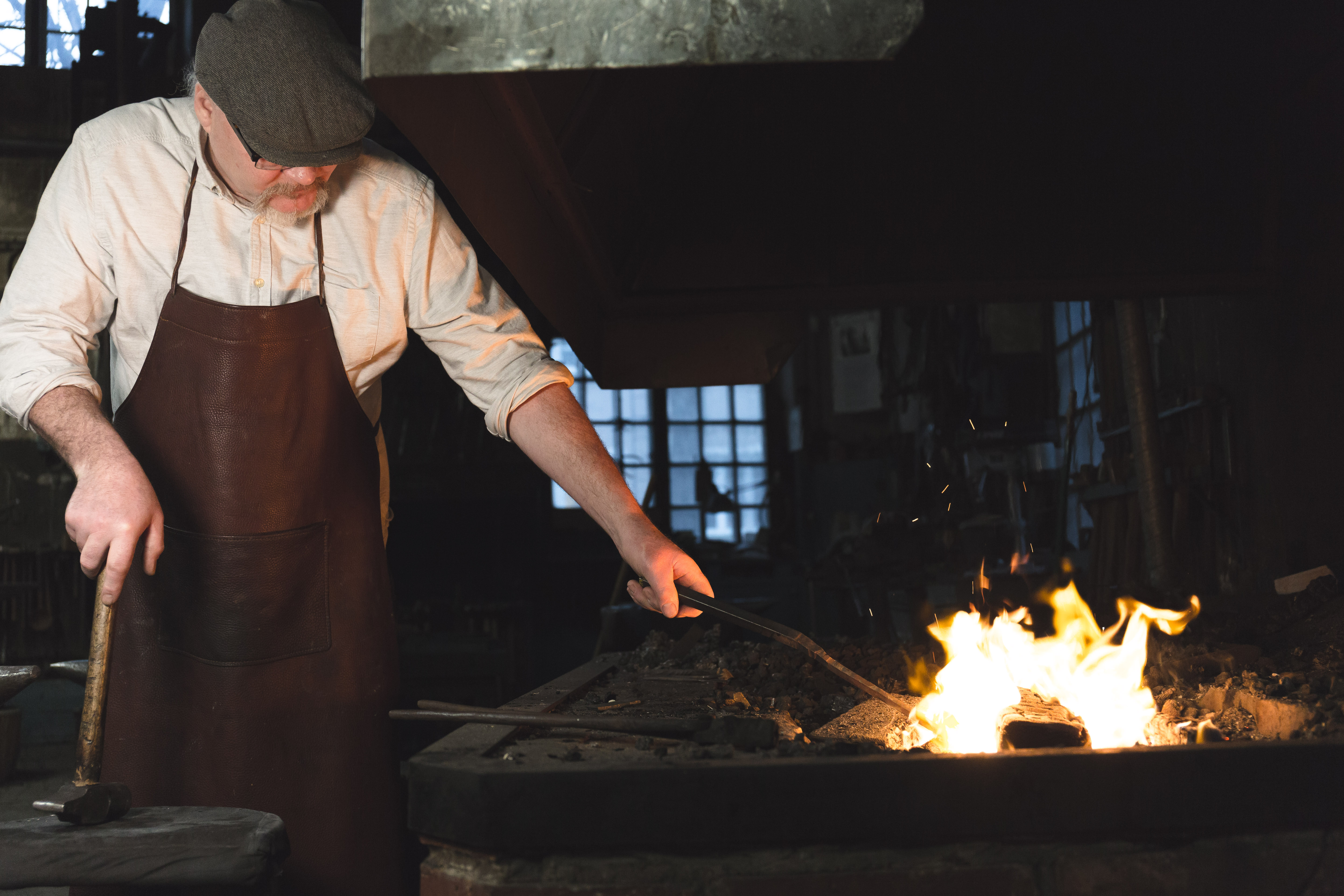 A man standing in the forge and warming steel in the fire at the Tidaholm Museum.