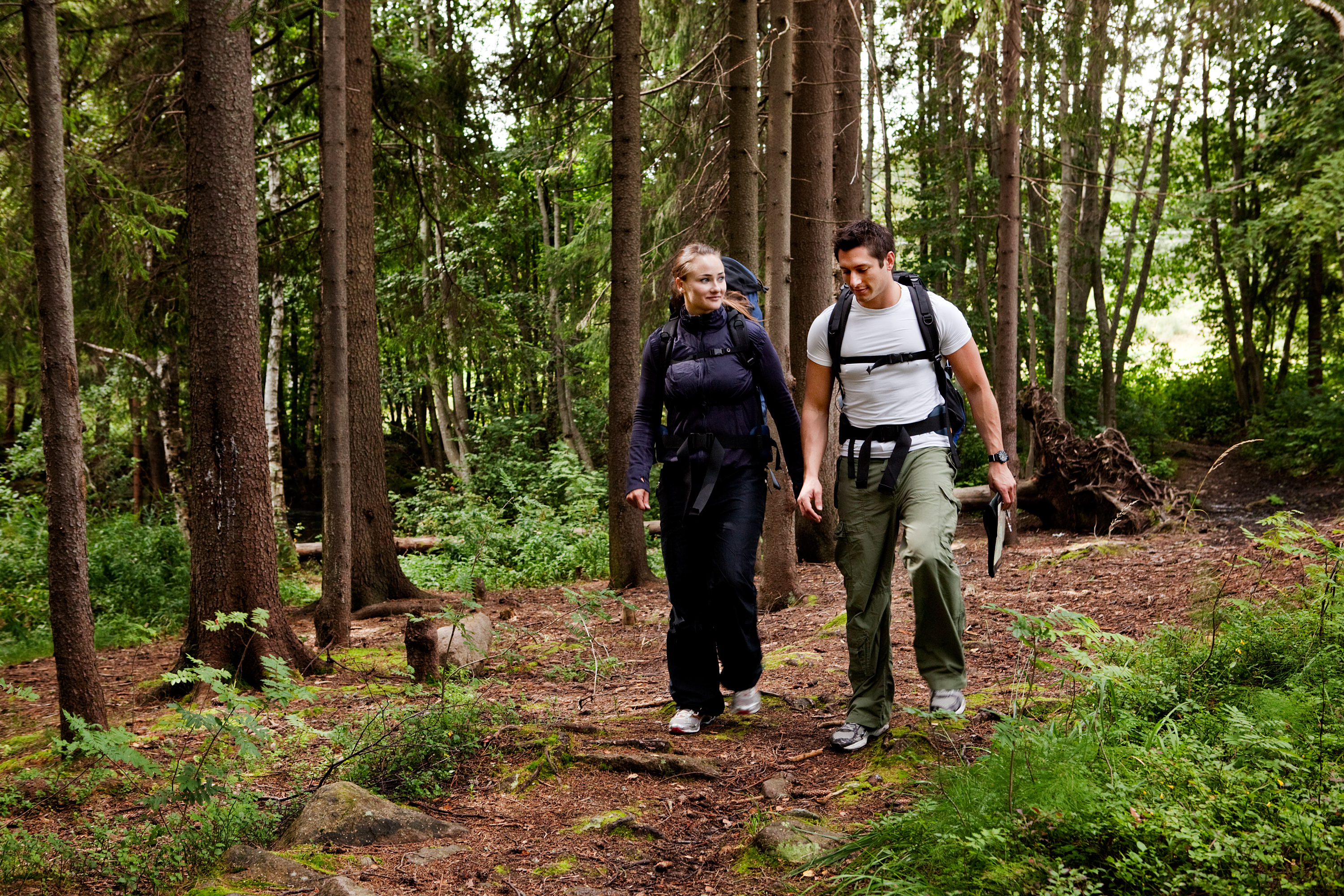 Two people walking on a path in the woods.