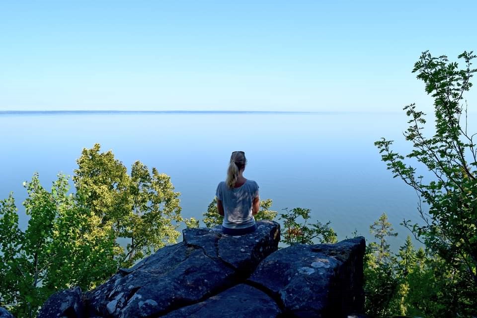 Woman meditates on Hallesnipen viewing point with a view of Lake Vänern.