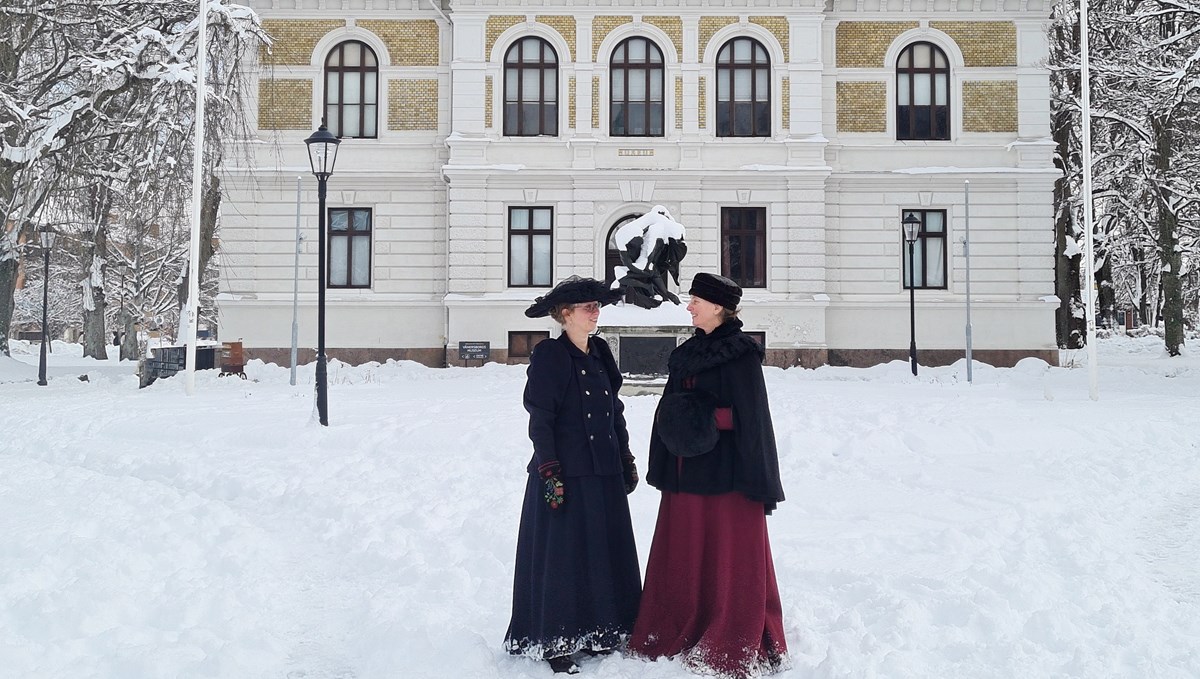 Photo taken of Vänersborg museum from the outside, surrounded with snow and two people in front of it, dressed in 19th-century outfits.