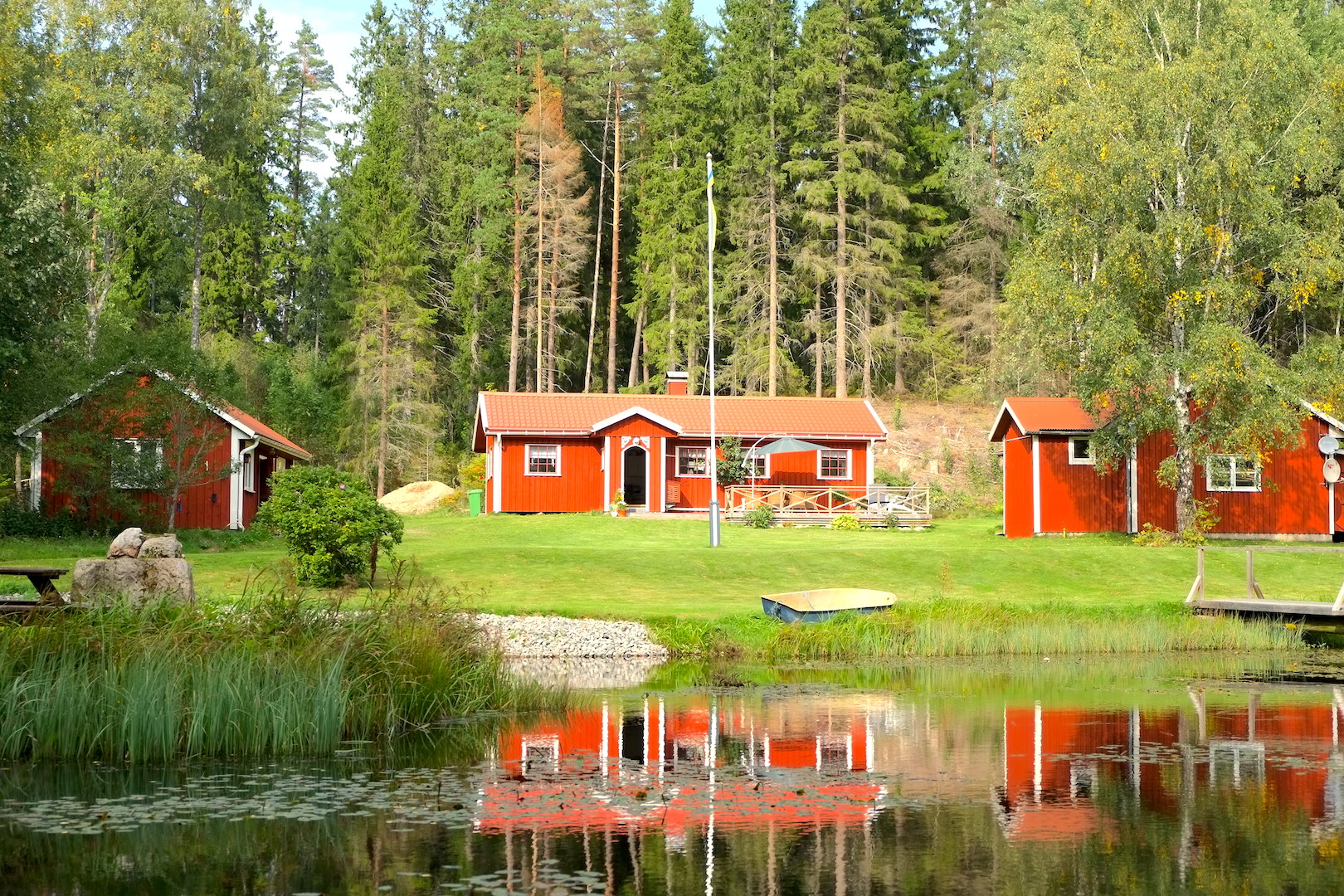 Three red woodenbuildings with a pond