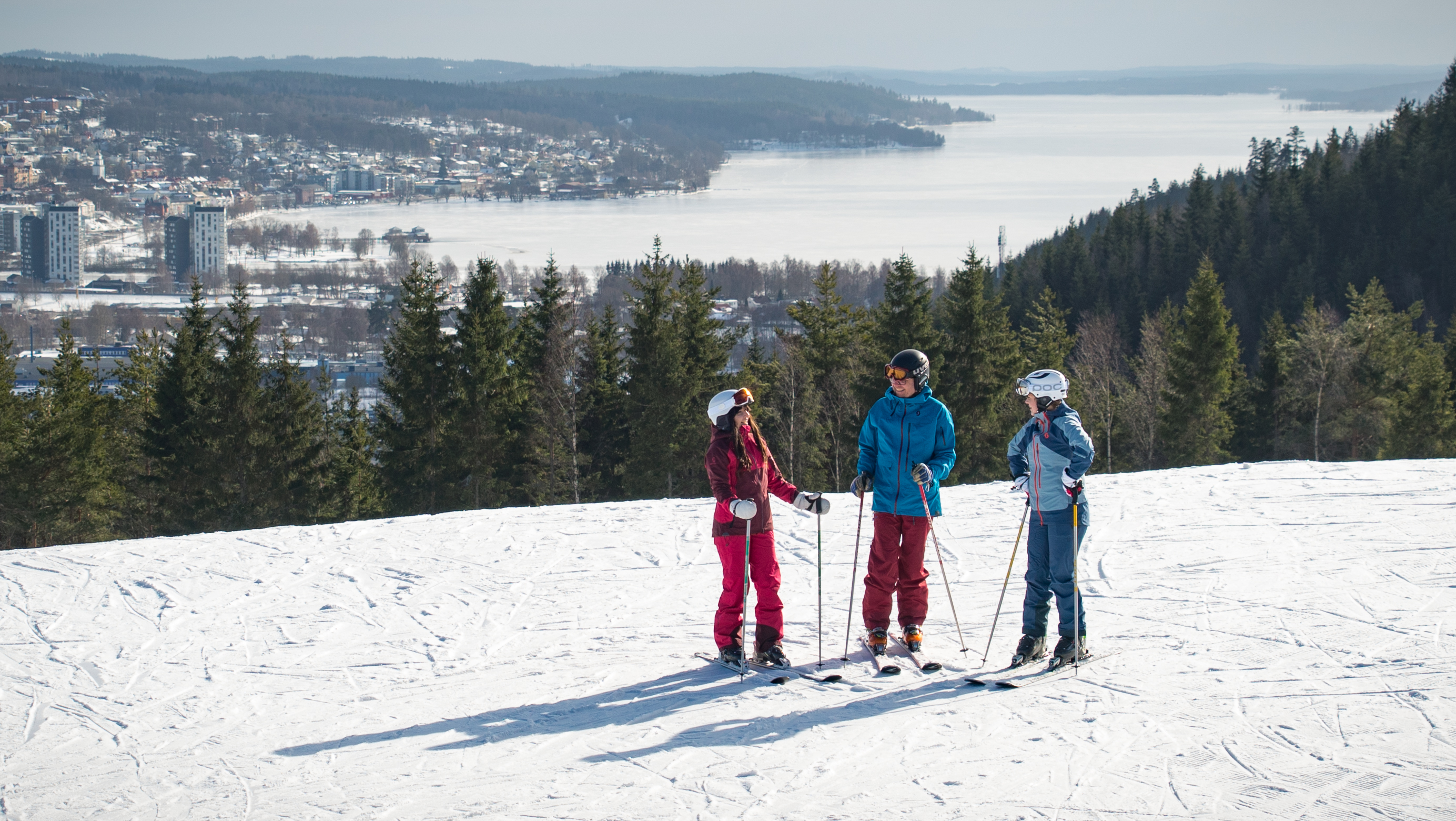 Three children in colorful clothes with skis on top of Ulricehamn Ski Center.