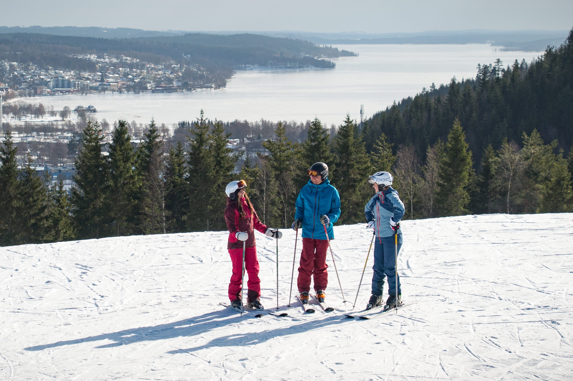 Three children in colorful clothes with skis on top of Ulricehamn Ski Center.
