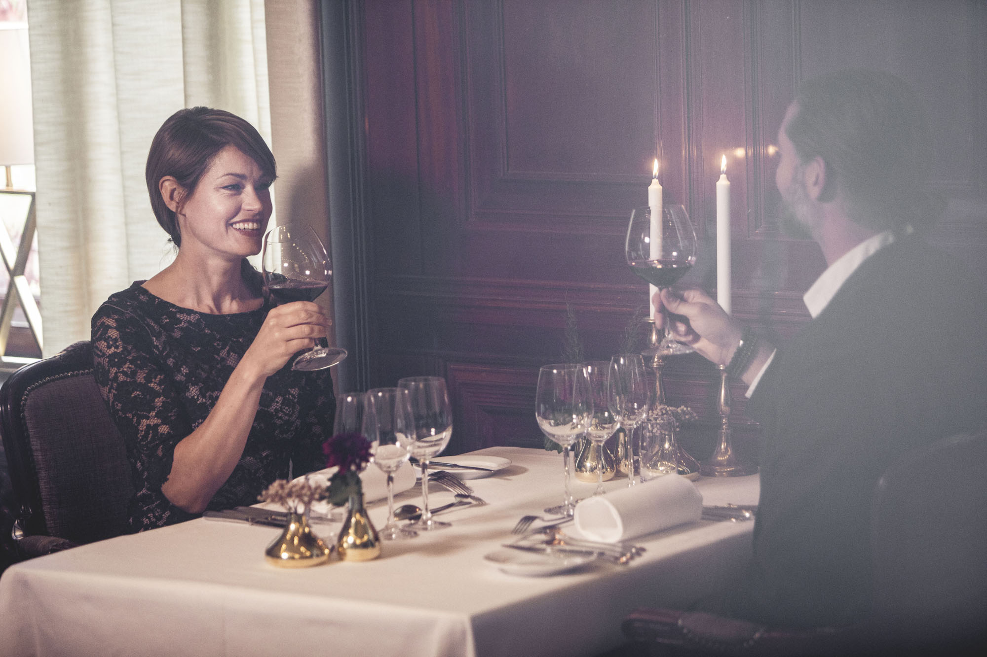 A woman and a man sitting at a table in a beautiful dining room. They toast
